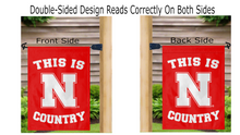 Load image into Gallery viewer, red university of nebraska garden flag with this is husker country logo displayed from both sides hung from a mailbox flagpole