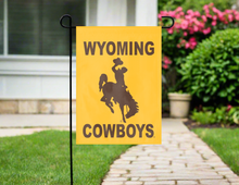 Load image into Gallery viewer, gold university of wyoming cowboys garden flag outside on a garden flag stand
