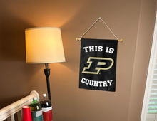 Load image into Gallery viewer, purdue garden flag with this is p country logo hung on a banner pole next to a lamp and drinks