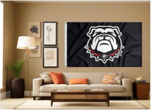 Load image into Gallery viewer, Black 3x5 foot wide university of Georgia flag with bulldogs logo and two metal grommets covering tan wall of well lit room