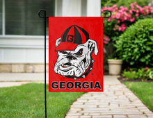 Load image into Gallery viewer, Georgia Bulldogs garden flag on a pole in front of a house with a pathway and flowers.