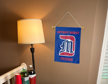 Load image into Gallery viewer, blue University of Detroit Mercy Titans Garden Flag hung from banner pole inside living room