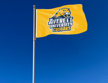 Load image into Gallery viewer, Gold 3x5 foot wide Averett University Cougars flag with two metal grommets attached to flagpole waving in the wind