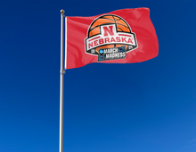 Load image into Gallery viewer, Red 3x5 Nebraska March Madness Flag with two metal grommets attached to flagpole waving in the wind