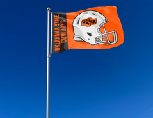 Load image into Gallery viewer, Black and Orange three by five foot wide Oklahoma State University Football Flag with two metal grommets attached to flagpole waving in the wind