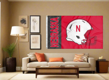 Load image into Gallery viewer, Red 3x5 University of Nebraska Football Flag with two metal grommets covering the tan wall fo a well-lit room