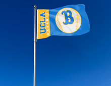 Load image into Gallery viewer, Blue and Gold 3x5 UCLA Baseball Flag with two metal grommets attached to flagpole waving in the wind