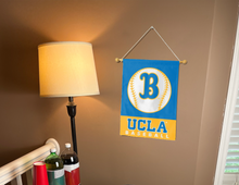 Load image into Gallery viewer, Blue and gold UCLA Baseball Garden Flag hanging on banner pole inside living room
