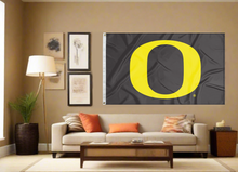 Load image into Gallery viewer, Black University of Oregon Flag with Gold O Logo hanging inside the living room behind the couch
