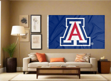 Load image into Gallery viewer, Blue 3x5 foot wide University of Arizona Flag with two metal grommets for indoor home decor covering tan wall of well-lit room