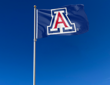 Load image into Gallery viewer, Blue 3x5 foot wide University of Arizona Flag with two metal grommets attached to flagpole waving in the wind for outdoor home decor
