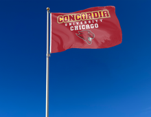 Load image into Gallery viewer, Red 3x5 foot wide Concordia University Chicago flag with Cougar Head Logo and two metal grommets attached to flagpole waving in the wind