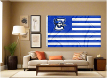 Load image into Gallery viewer, 3x5 feet wide Creighton University Flag with seven blue stripes and six white stripes and two metal grommets covering the tan wall inside of a well organized room with couch pillows and light