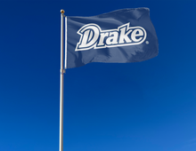 Load image into Gallery viewer, Blue 3x5 foot wide Drake University Flag with Drake Logo and two metal grommets attached to flagpole waving in the wind