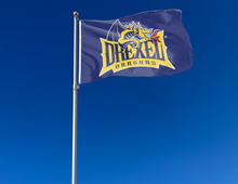 Load image into Gallery viewer, Blue 3x5 foot wide Drexel University Dragons Flag with Drexel dragons logo and two metal grommets attached to flagpole waving in the wind