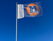 Load image into Gallery viewer, Two Panel Blue and Gray Duke University 3x5 foot wide Flag with Duke Basketball Logo and two metal grommets attached to flagpole waving in the wind