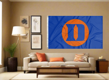 Load image into Gallery viewer, Blue Duke University 3x5 Flag with D Logo and Basketball Logo and two metal grommets covering the tan wall of the living room