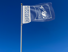 Load image into Gallery viewer, 3x5 foot wide Blue and Gray 2 Panel Duke University Flag with Duke Logo Blue Devils Logo and two metal grommets attached to flagpole waving in the wind