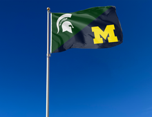 Load image into Gallery viewer, green and blue MSU Michigan house divided flag attached to flagpole waving in the wind