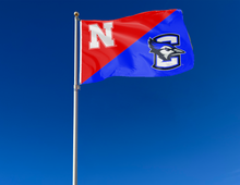 Load image into Gallery viewer, red and blue Nebraska Creighton House divided flag attached to flagpole waving in the wind