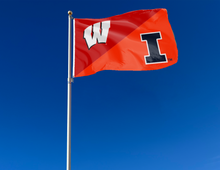 Load image into Gallery viewer, red and orange House Divided flag with Wisconsin Illinois Game logo and two metal grommets attached to flagpole waving in the wind