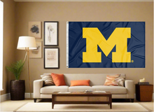 Load image into Gallery viewer, Blue University of Michigan Flag hung inside well-lit room