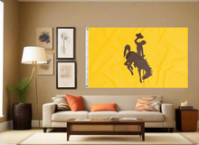 Load image into Gallery viewer, Gold university of Wyoming flag displayed inside well lit college dorm for man cave decor
