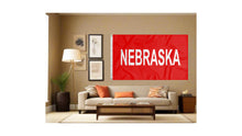 Load image into Gallery viewer, red Nebraska huskers flag with Nebraska wordmark logo displayed inside well-lit room