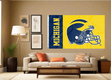 Load image into Gallery viewer, University of Michigan Football Flag with covering the tan wall of a well-lit room