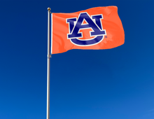 Load image into Gallery viewer, Orange 3x5 foot wide Auburn University Flag with Blue AU Logo and Two Metal Grommets attached to flagpole waving in the wind
