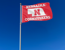 Load image into Gallery viewer, Nebraska Cornhuskers flag with state of Nebraska border logo attached to flagpole waving in the wind
