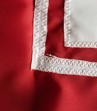 Load image into Gallery viewer, Close up shot of white hand-sewn nebraska huskers logo on red university of nebraska applique flag