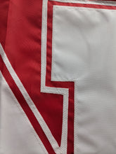 Load image into Gallery viewer, Close up shot of white hand-sewn nebraska huskers logo on red university of nebraska applique flag