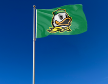 Load image into Gallery viewer, Green University of Oregon flag with Oregon Duck logo attached to flagpole waving in the wind