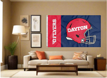 Load image into Gallery viewer, Blue and red two striped University of Dayton Flyers Football flag and two metal grommets covering the tan wall inside of a well organized room with couch pillows and light