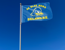 Load image into Gallery viewer, Blue 3x5 foot wide University of Delaware Flag with go blue hens Delaware logos and two metal grommets attached to flagpole waving in the wind