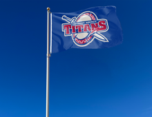 Load image into Gallery viewer, Blue 3x5 foot University of Detroit Mercy Flag with Titans sword and shield logos and two metal grommets attached to flagpole waving in the wind