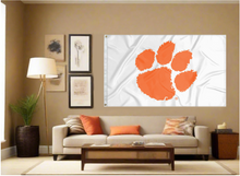 Load image into Gallery viewer, white 3x5 foot wide Clemson University Flag with two metal grommets covering the tan wall inside of a well organized room with couch pillows and light