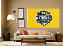 Load image into Gallery viewer, indoor display of gold michigan 2026 march madness basketball champions flag as part of man cave decor