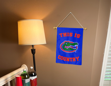 Load image into Gallery viewer, indoor display of this is florida gators country garden flag inside college dorm