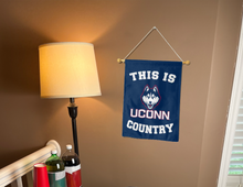 Load image into Gallery viewer, this is uconn country garden flag hung inside for college dorm decor