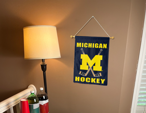university of Michigan Hockey garden flag hanging on a wall next to a lamp and drinks.