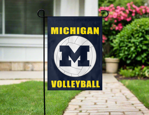 blue Michigan Volleyball garden flag in front of a house with a pathway and flowers.