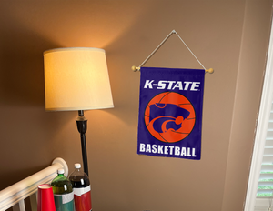 purple kansas state basketball garden flag hung on a banner pole next to a lamp and drinks