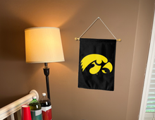 Load image into Gallery viewer, black university of Iowa garden flag hanging on banner pole inside living room
