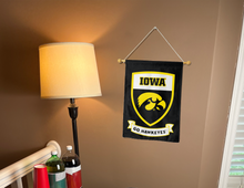 Load image into Gallery viewer, iowa hawkeyes shield logo and go hawkeyes logos garden flag hung on banner pole next to a lamp and drinks

