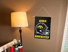 Load image into Gallery viewer, iowa hawkeyes football garden flag hanging on banner pole next to a lamp and a few drinks

