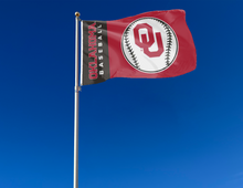 Load image into Gallery viewer, black and red University of Oklahoma baseball flag with two metal grommets attached to flagpole waving in the wind
