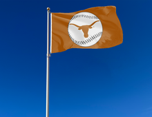 Load image into Gallery viewer, Orange University of Texas Baseball Flag with two metal grommets attached to flagpole waving in the wind
