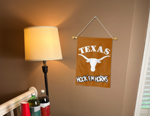 Load image into Gallery viewer, university of Texas garden flag with hook em horns logo hanging on banner pole inside living room
